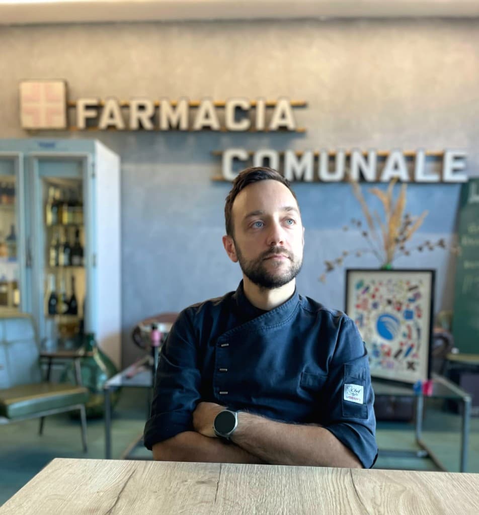 Chef Luca Matarazzo at LaFarmacia Bistrot, with the historic Farmacia Comunale sign behind him